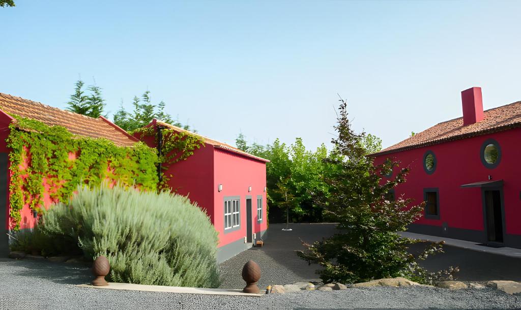 two red buildings with plants in a courtyard at Big Red Barn - Spectacular Villa in Sancheira
