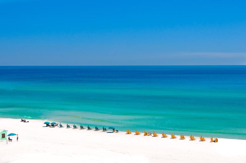 a beach with a line of chairs and the ocean at Sunny and Share in Destin