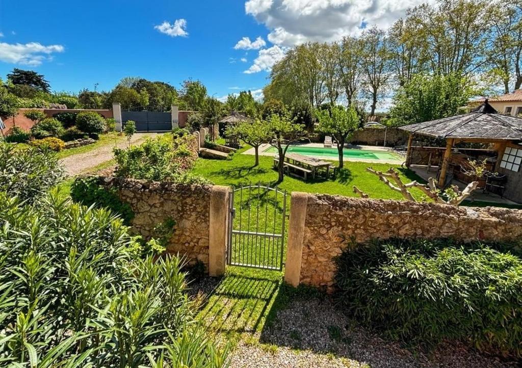 ein Garten mit Steinzaun und ein Golfplatz in der Unterkunft Le jardin secret bnb in Villeneuve-lès-Béziers