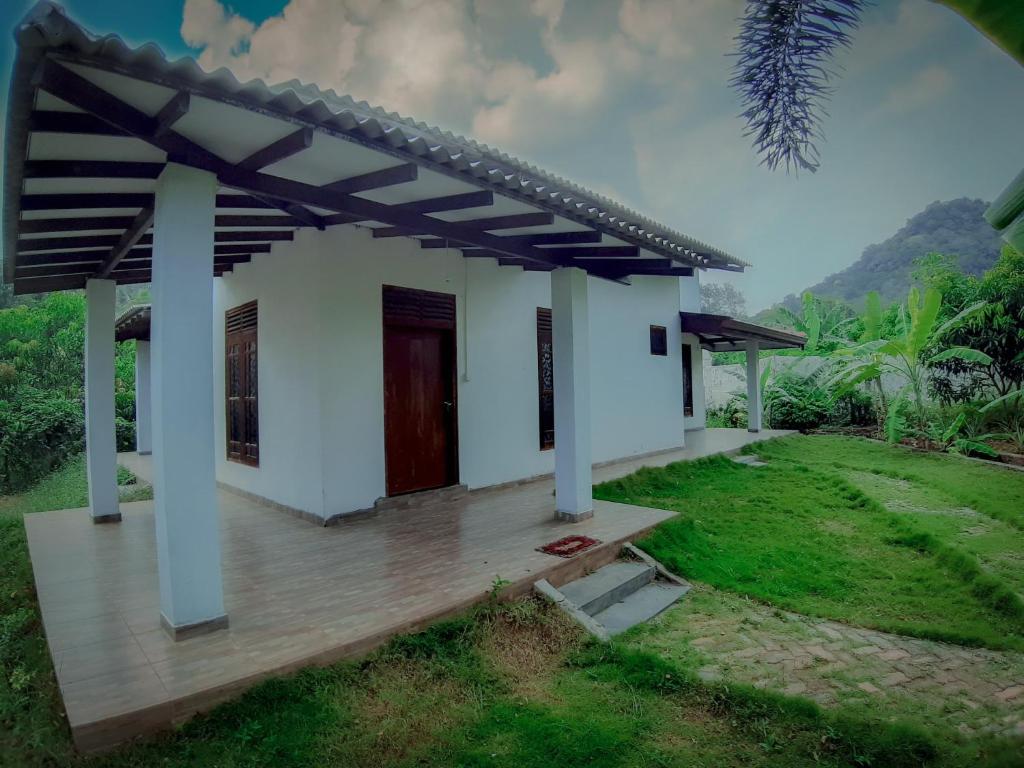 a small white house with a wooden deck at Adithya Resort in Nikawatawana