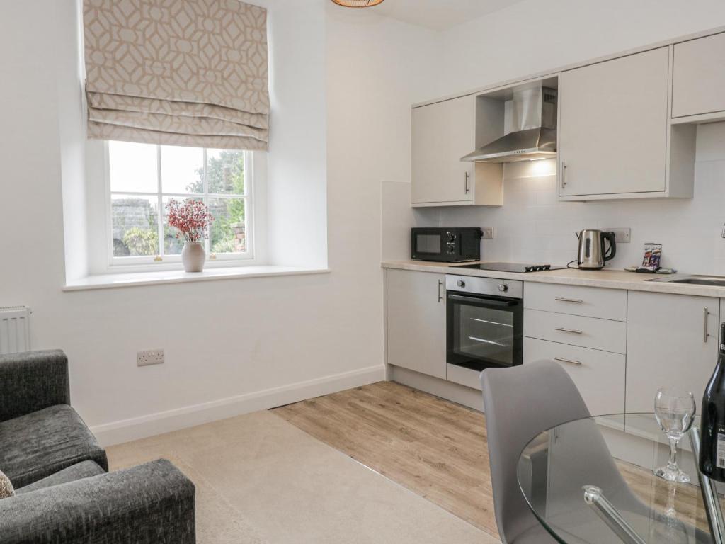 a kitchen with white cabinets and a glass table at Ullswater in Ulverston