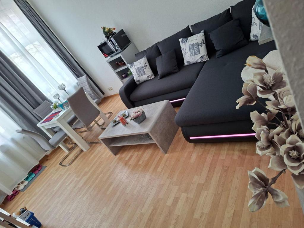 ein Wohnzimmer mit einer schwarzen Couch und einem Tisch in der Unterkunft Citystudio Neuwied mit Schlafgalerie bis 5 Gäste direkt am Luisenplatz in Neuwied