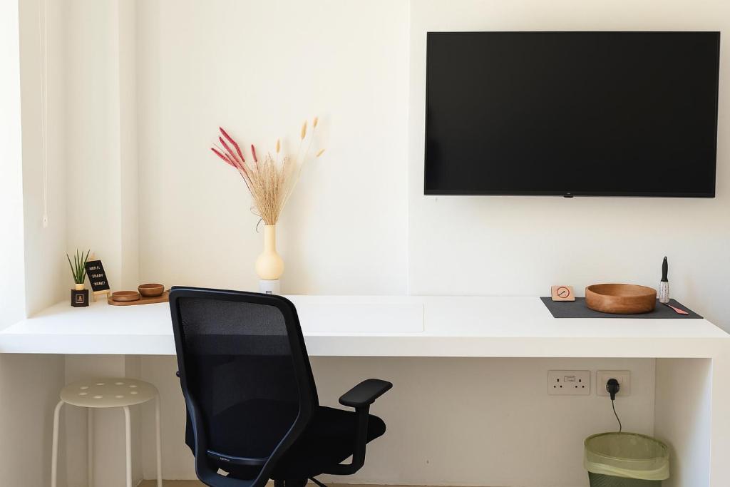 a desk with a chair and a television on a wall at Central House in Limassol
