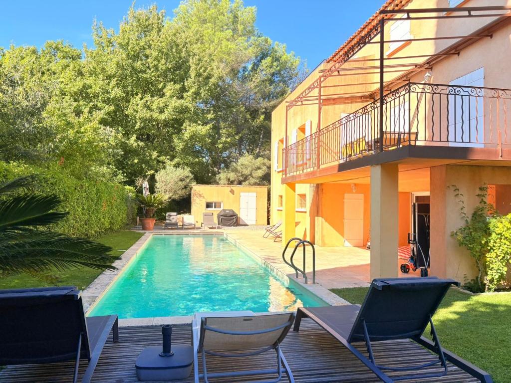 a swimming pool with chairs and a house at la grande villa in Aix-en-Provence
