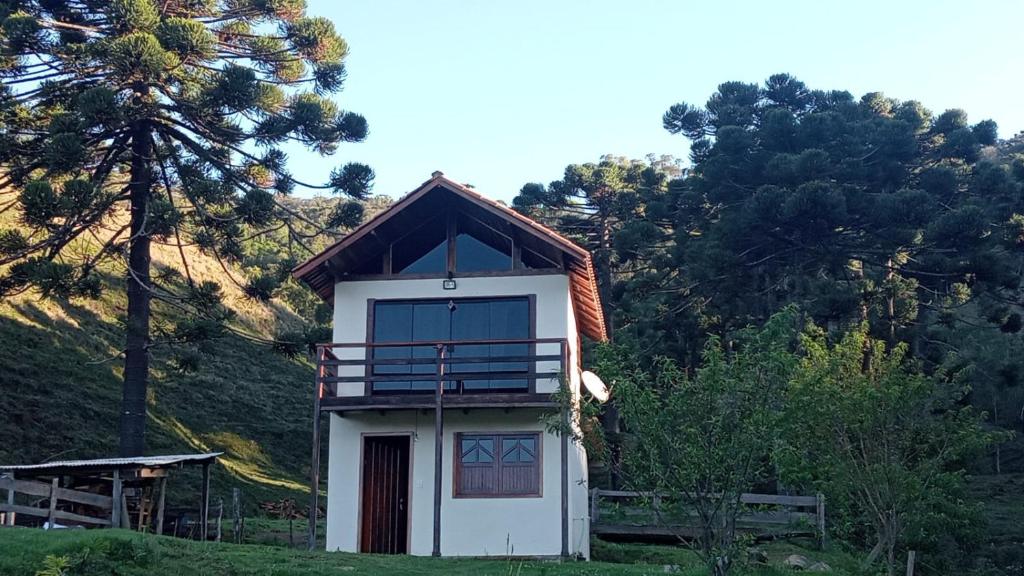 ein kleines weißes Haus mit einem Gameradach in der Unterkunft Sítio Araucária in Itamonte
