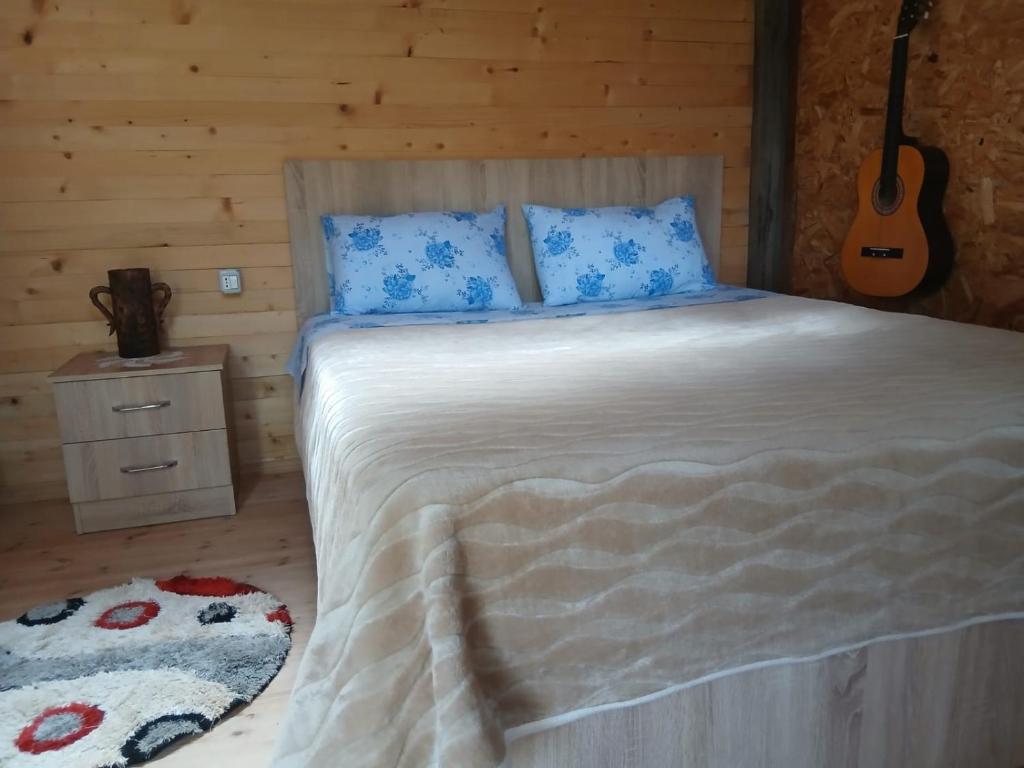 a bed with blue pillows and a guitar in a room at Bujtina Liqeni i Shkopetit in Madhesh