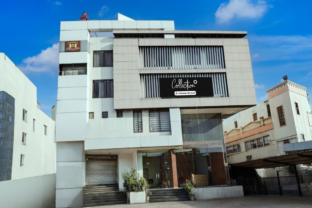 a tall white building with a black sign on it at Collection O Motipura Bus Terminal Formerly Hotel Navjivan in Himatnagar