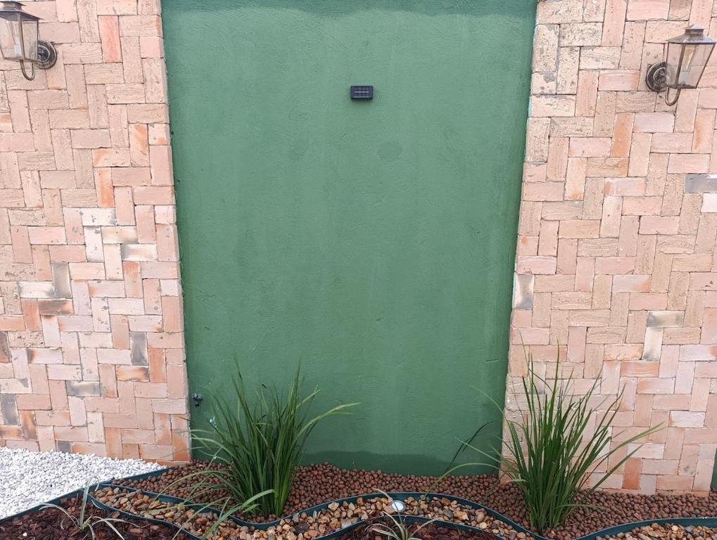 a green door on a building with two plants at Espaço jr in Andradina
