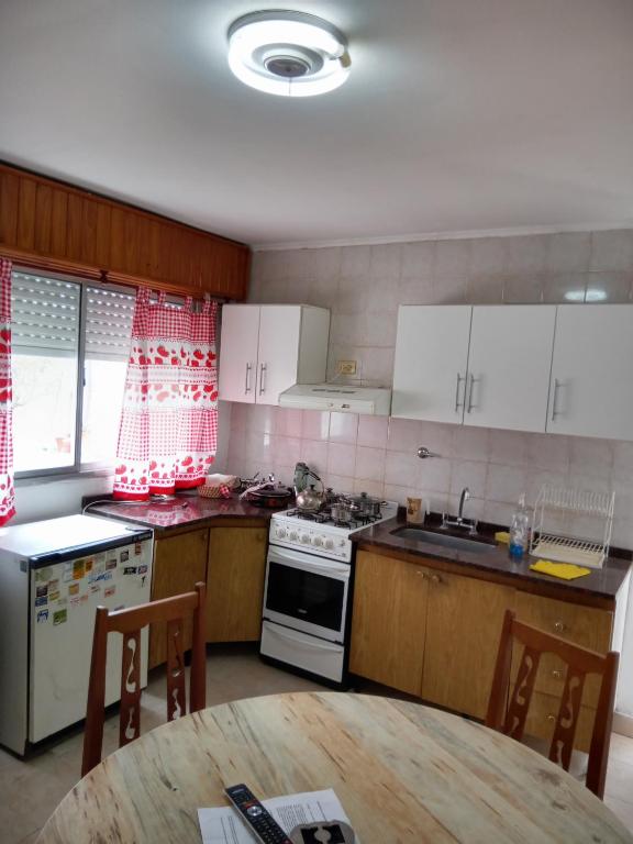 een keuken met witte kasten, een tafel en een fornuis bij Depto cómodo y confortable in Olavarría