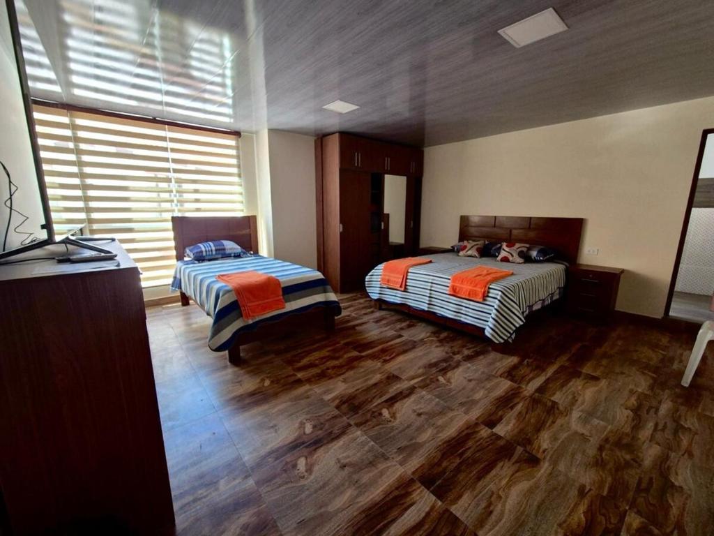 two beds in a room with wooden floors at Modern, comfortable and convenient space in Sucre