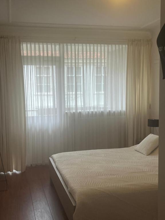 a bedroom with a white bed with white curtains at Franciscus in Bergen op Zoom