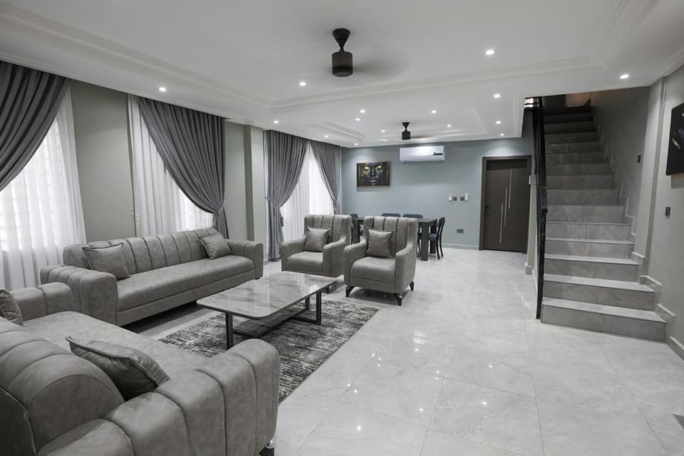 una gran sala de estar con sofás y una escalera. en BMS Lodge, en Kumasi