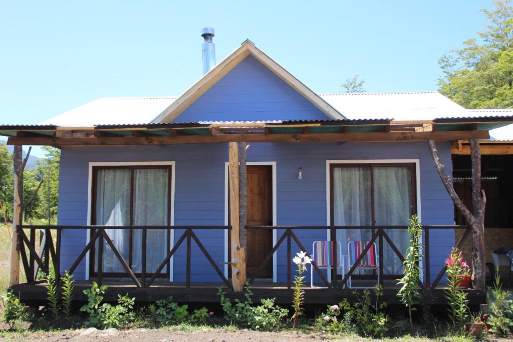 a blue house with a porch and two chairs at Cabaña 1 Dos Laureles in Panguipulli