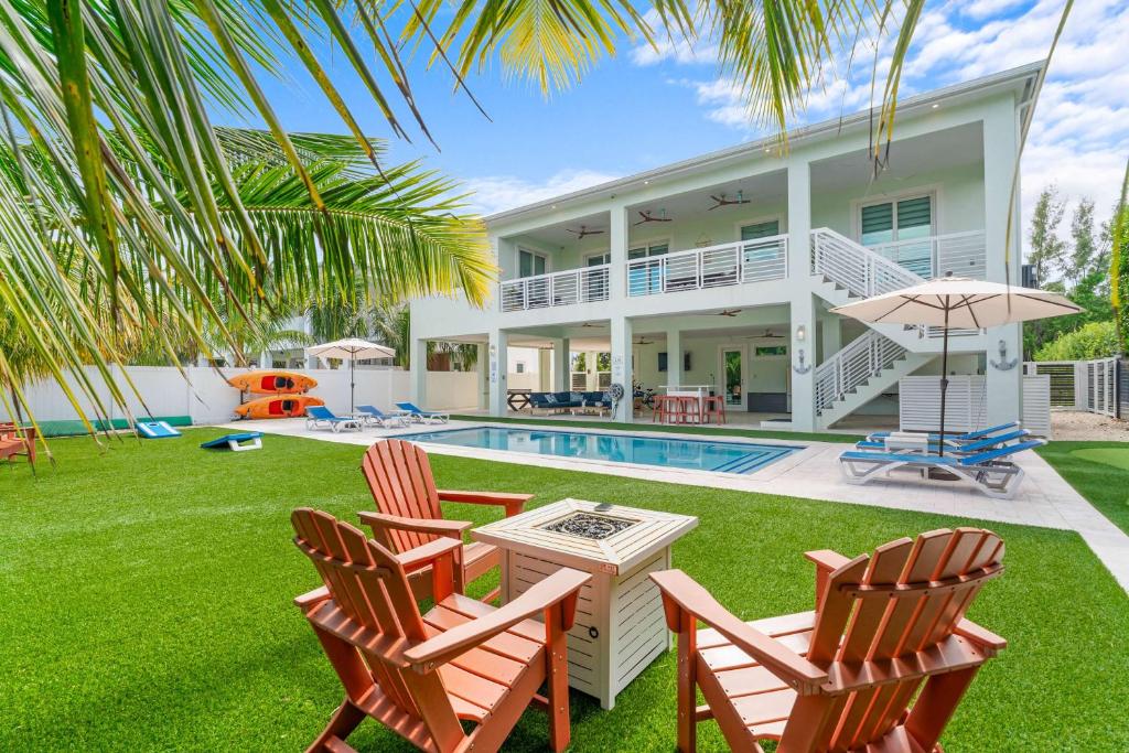 a villa with a swimming pool and two lawn chairs at Emerald Oasis Deluxe Waterfront Gem, Heated Pool with Dock in Marathon