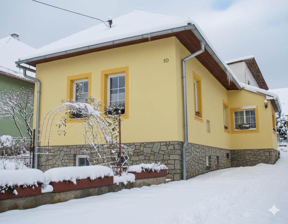 een geel huis met sneeuw op de grond bij Žltý domček - Apartmán Švábovce in Svabovice