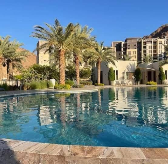 a large swimming pool with palm trees and buildings at قرية الراحه مرسى زايد in Al Burj