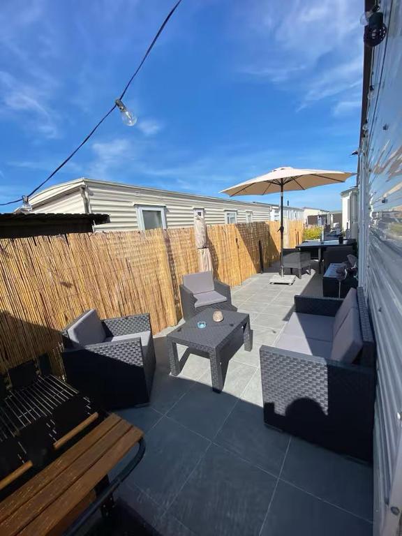 a patio with tables and chairs and an umbrella at Chalet D'Mar in Wenduine