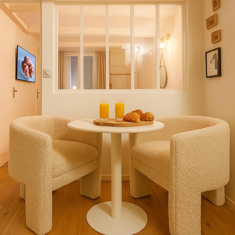 a table with two chairs and two glasses of orange juice at Night Desires vieille ville Annecy charmant in Annecy