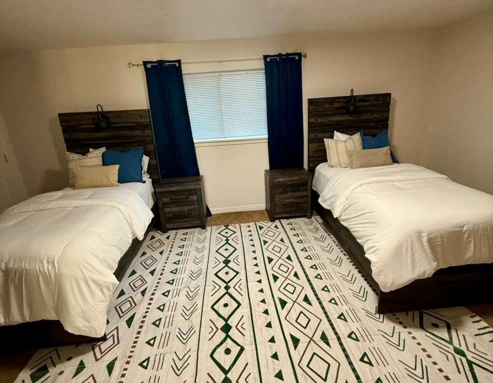 two beds in a room with blue curtains at Cozy and well located 2-bedroom basement in Provo