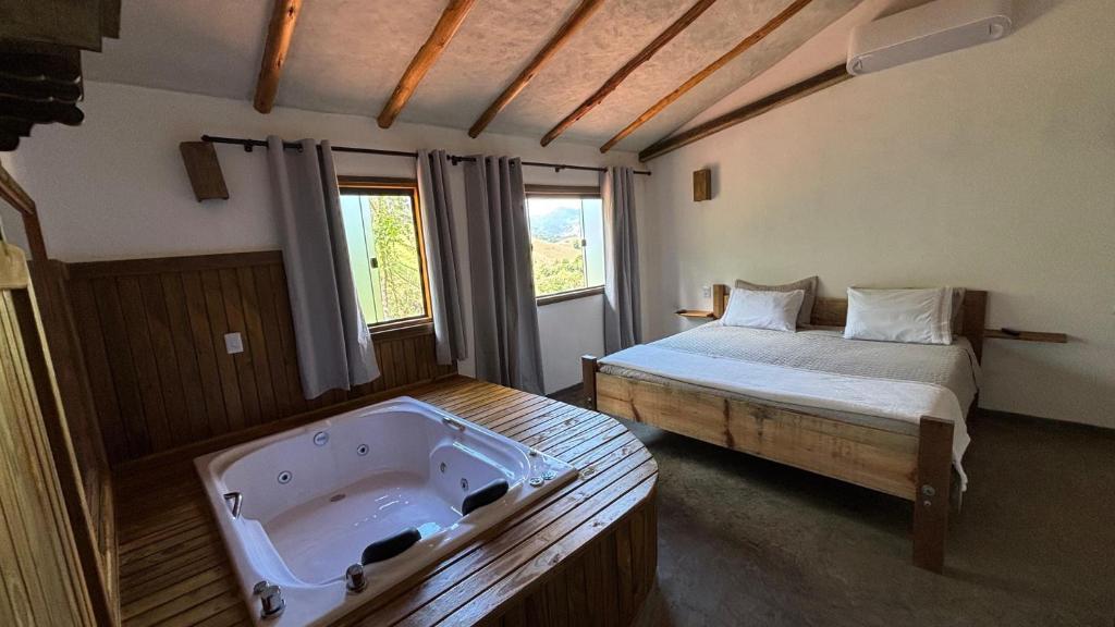 a bedroom with a bed and a bath tub at Pousada Verde Serena SFX in São Francisco Xavier