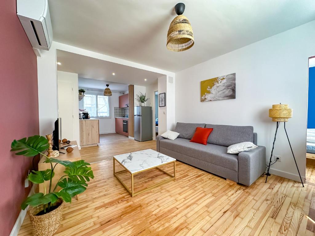 ein Wohnzimmer mit Sofa und Tisch in der Unterkunft L'aube Climatisation Parking 2 chambres in Grenoble