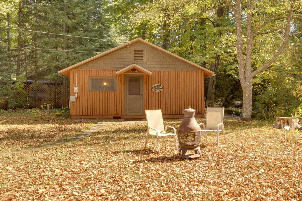 ein Haus mit einer Vase und Stühlen im Garten in der Unterkunft Cozy Rivershire Retreat Cabin Near Traverse City in Devils Elbow