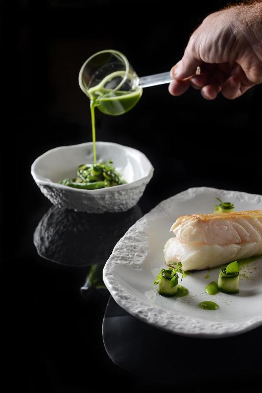 a person is pouring sauce on a plate of food at Le Kaïla in Méribel