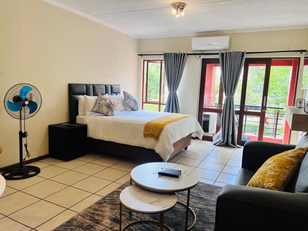 een slaapkamer met een bed, een bank en een tafel bij Rockmel Apartment in Sandton