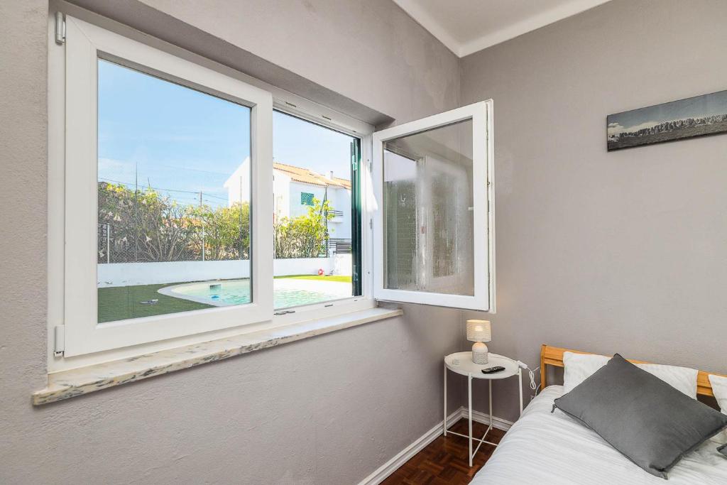 a bedroom with a bed and a large window at Private Room in Family Home with Pool in Sesimbra