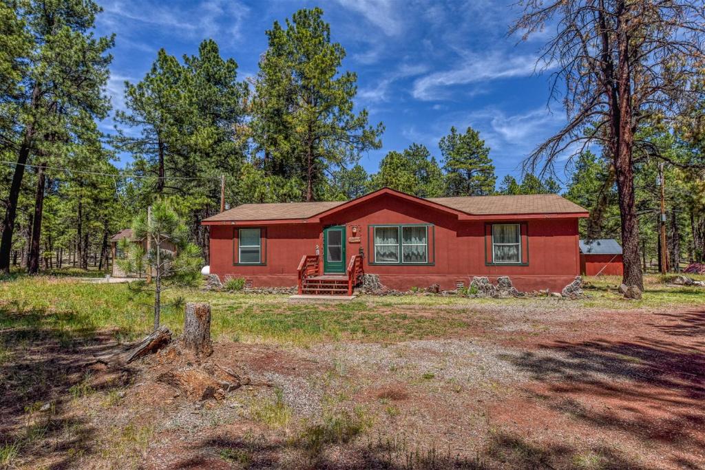 a red house in the middle of a forest at Gorgeous Historic 3 BR Log Cabin w Forest Views 20 Minutes from Flagstaff Now with Wi-Fi in Parks