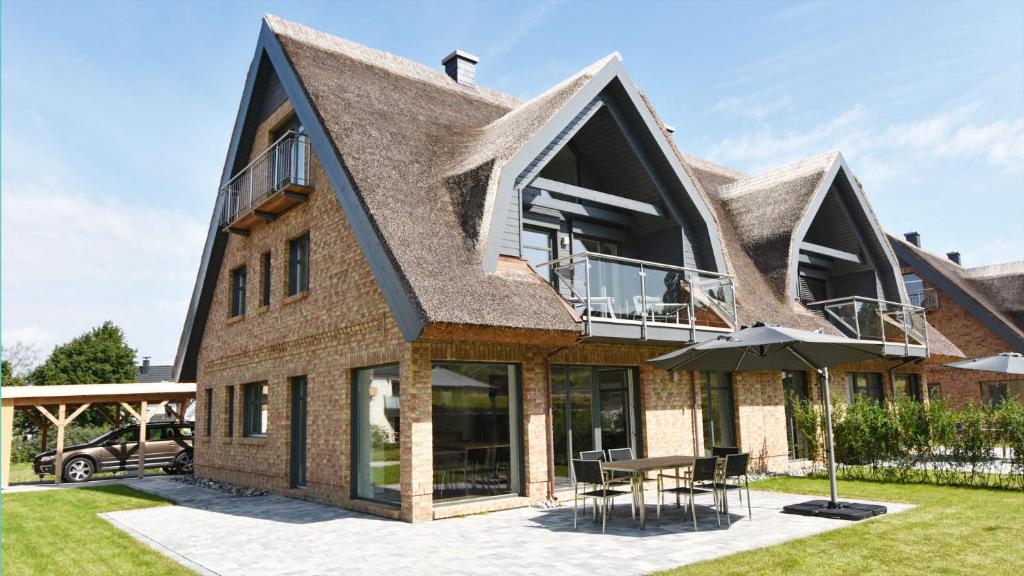 a house with a roof that has a table and an umbrella at Exklusive Reetdach-Villa Ostseefrische in Lobbe