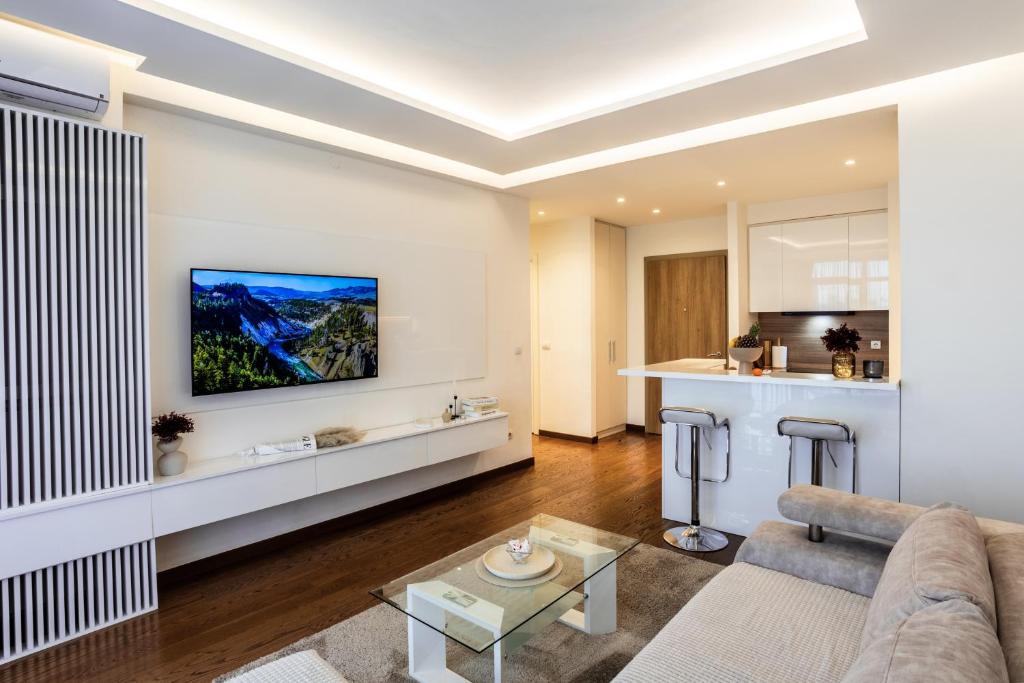 Una sala de estar con un sofá y un televisor en una pared. en Bw Zuma Apartments, en Belgrado