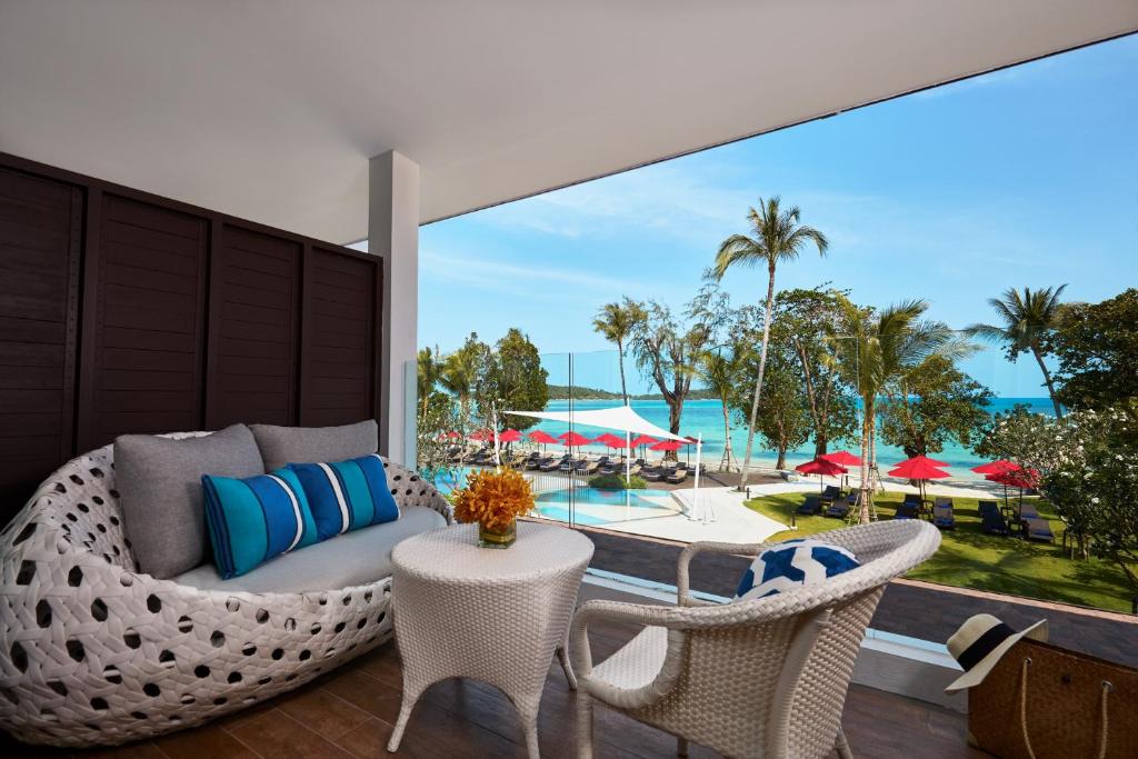 a patio with a couch and chairs and a view of a pool at Amari Koh Samui in Chaweng