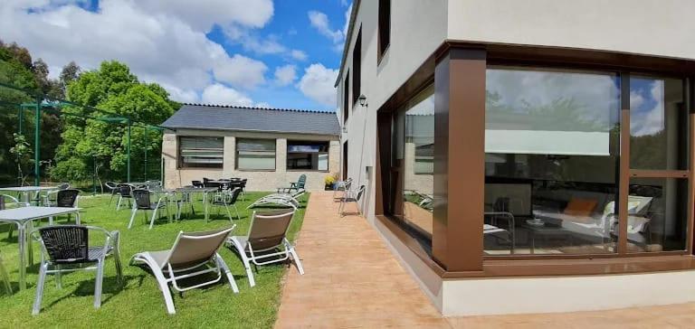 een patio met stoelen en tafels in een tuin bij Albergues O Abrigo Miraz 