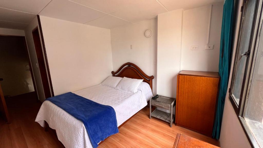 a bedroom with a bed with a blue blanket on it at El Gran Hotel in Chiquinquirá