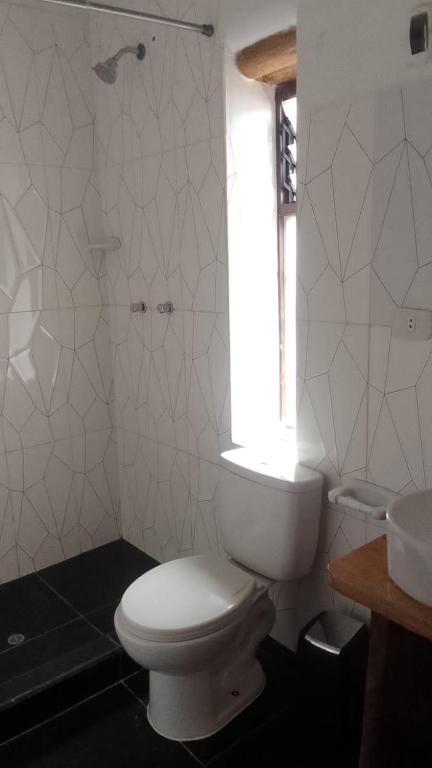 a white bathroom with a toilet and a window at Casa tarawasy hostel in Urubamba