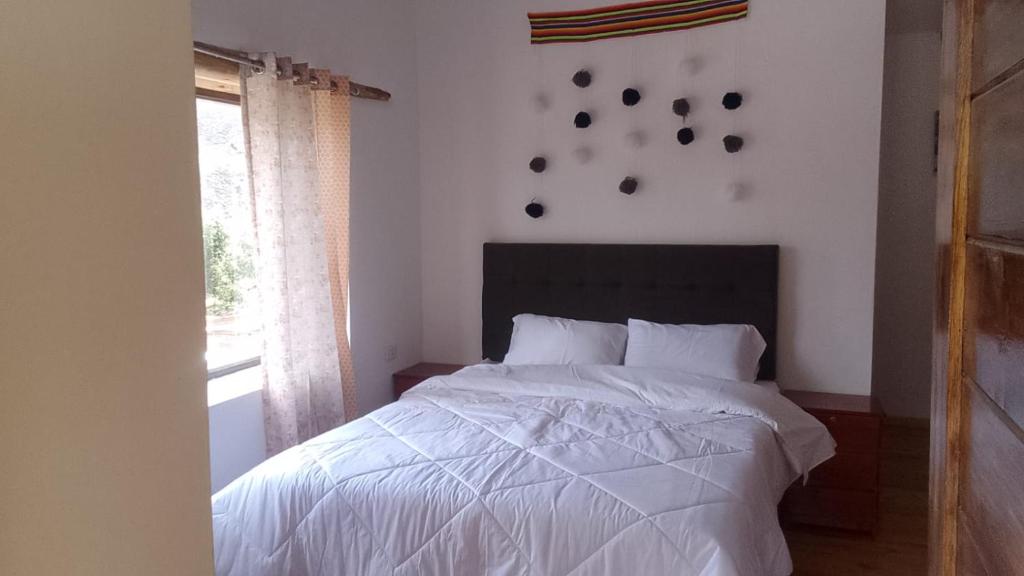 una camera da letto con un letto bianco e una finestra di Casa tarawasy hostel a Urubamba
