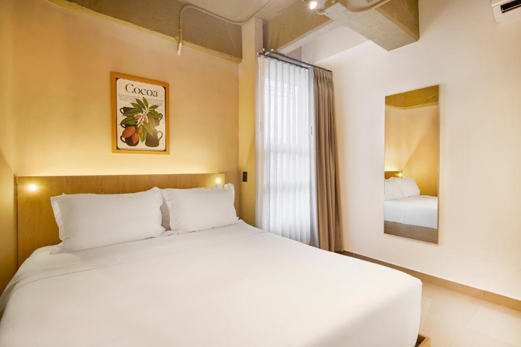 a bedroom with a white bed and a window at Hotel Attic 33 in Medellín