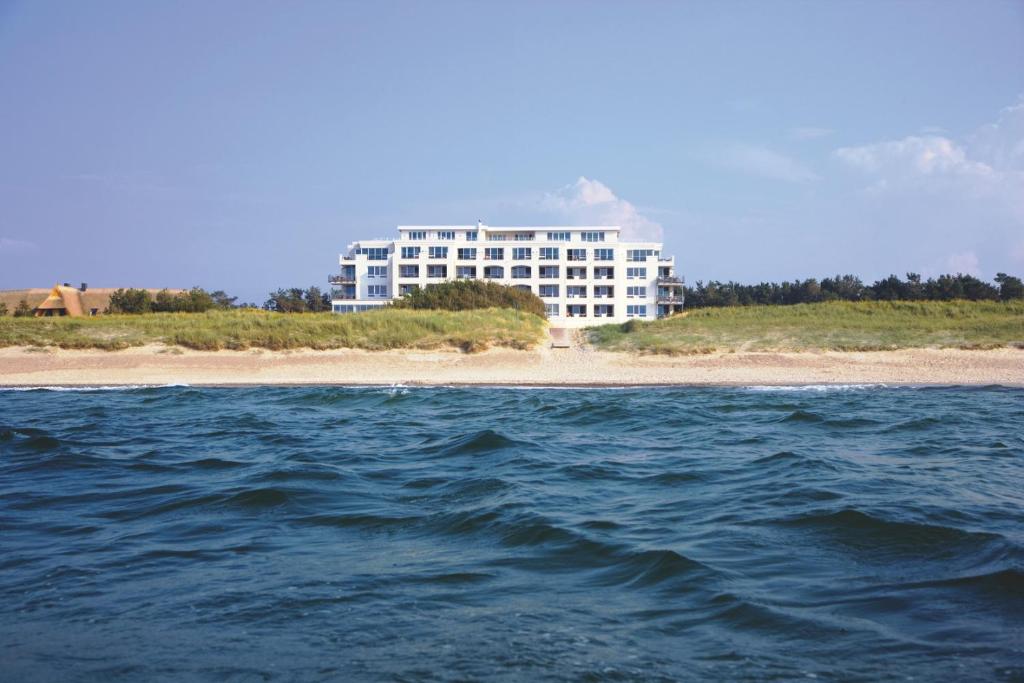 een groot gebouw aan het strand naast de oceaan bij Strandhotel Dünenmeer - Adults only in Dierhagen