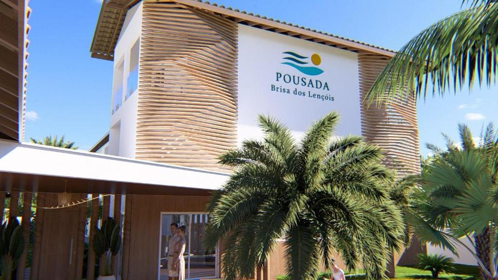 a palm tree in front of a building with a sign at Pousada Brisa dos Lençóis in Barreirinhas