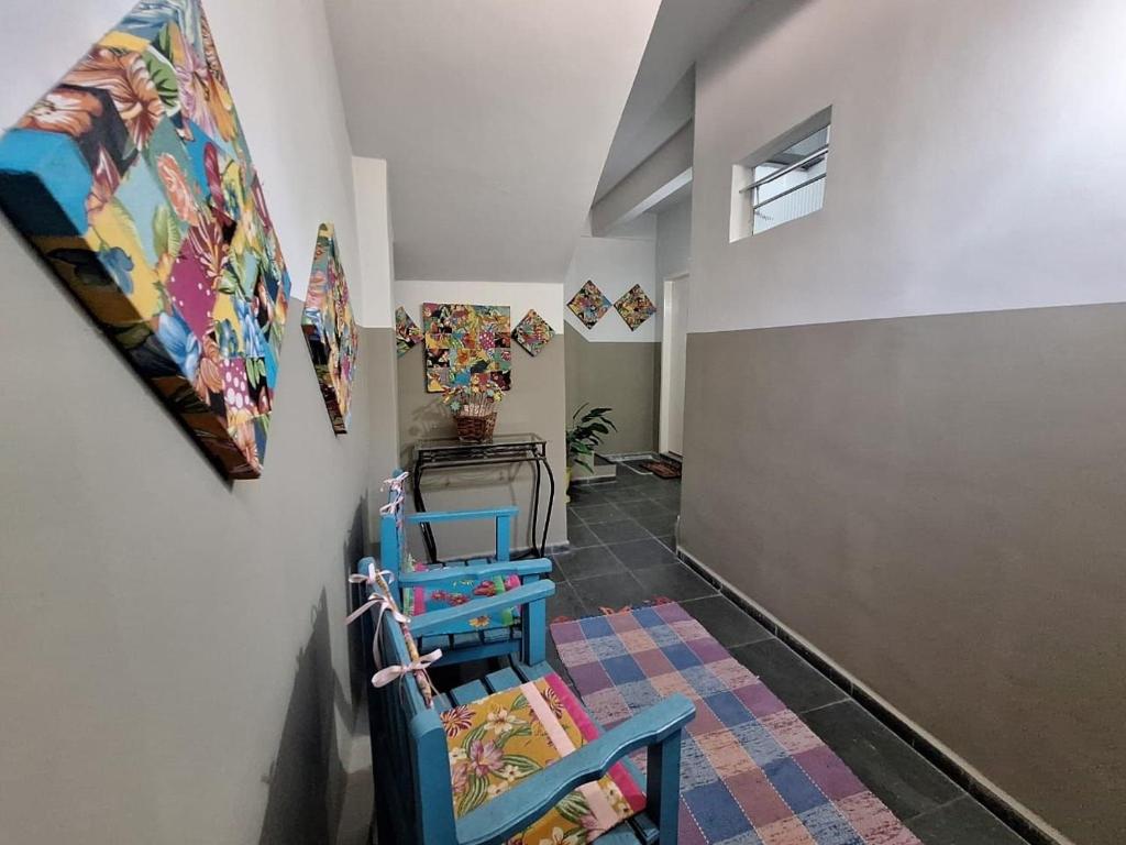 a hallway with two blue chairs and paintings on the wall at Apartamento Estúdio em Volta Redonda - RJ in Volta Redonda