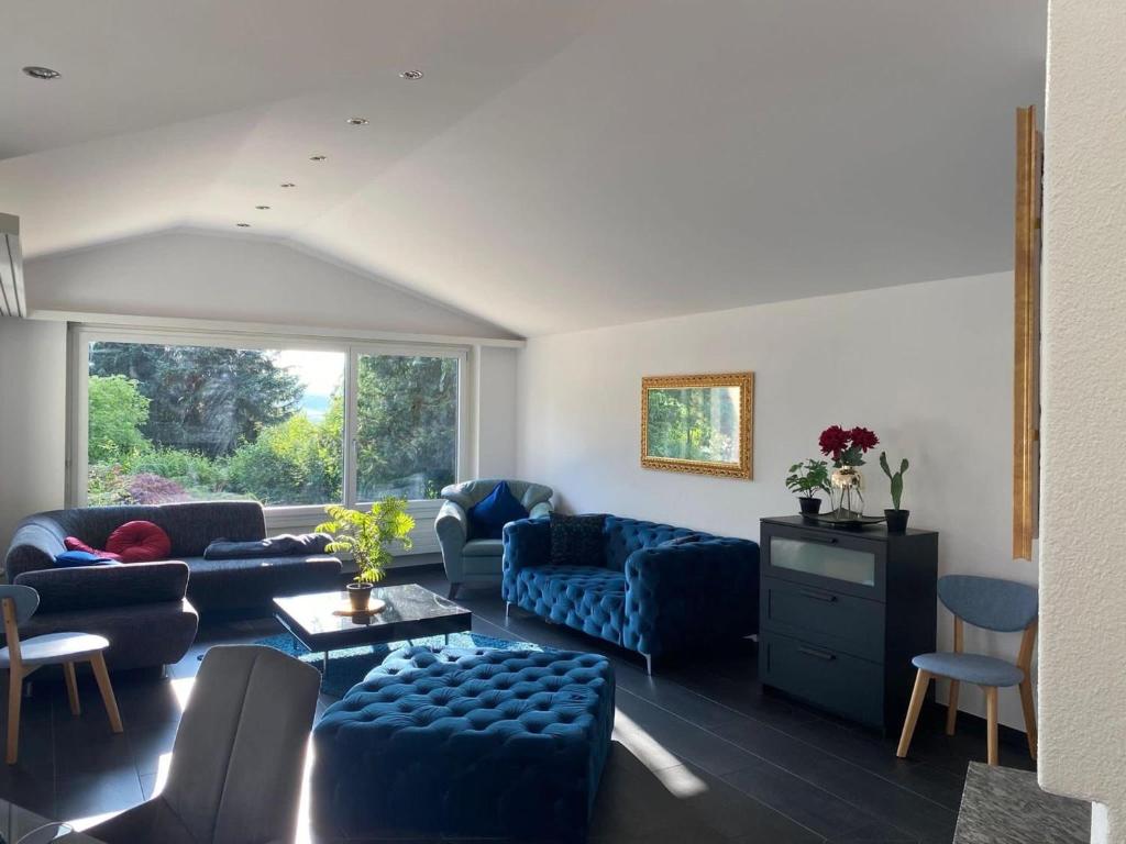a living room with blue furniture and a large window at Stay Inn - Meisterschwanden in Meisterschwanden