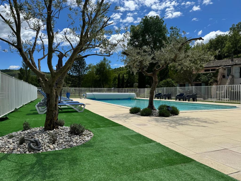 a swimming pool with two trees in a yard at Gîte Le Nathalie Meublé de tourisme 4 étoiles Le Moulin de Prédelles in Reillanne