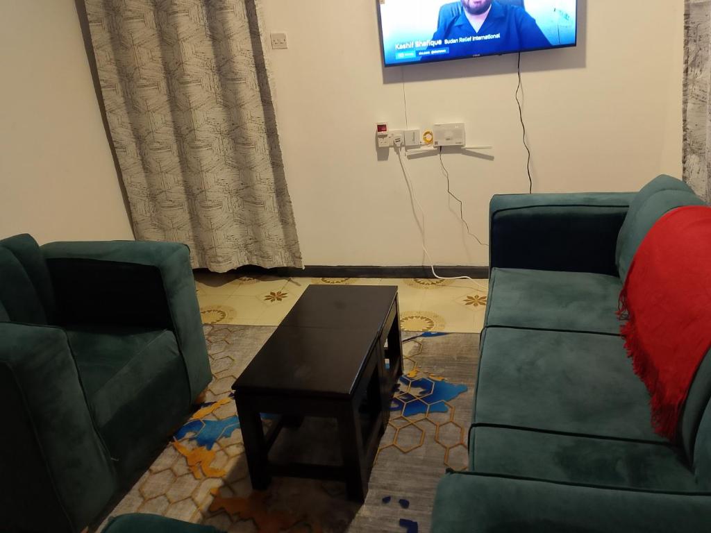 a living room with two green chairs and a table at The Pent House Homes in Kisii
