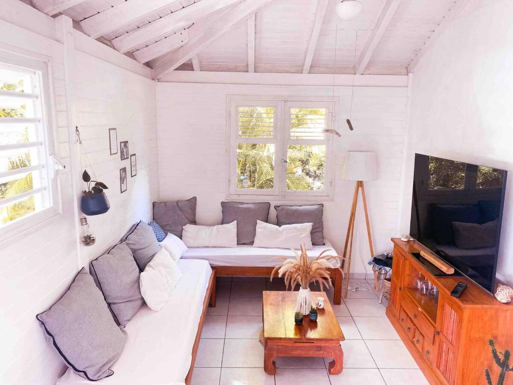 a living room with a couch and a tv at Iguane Bungalow in Saint-François