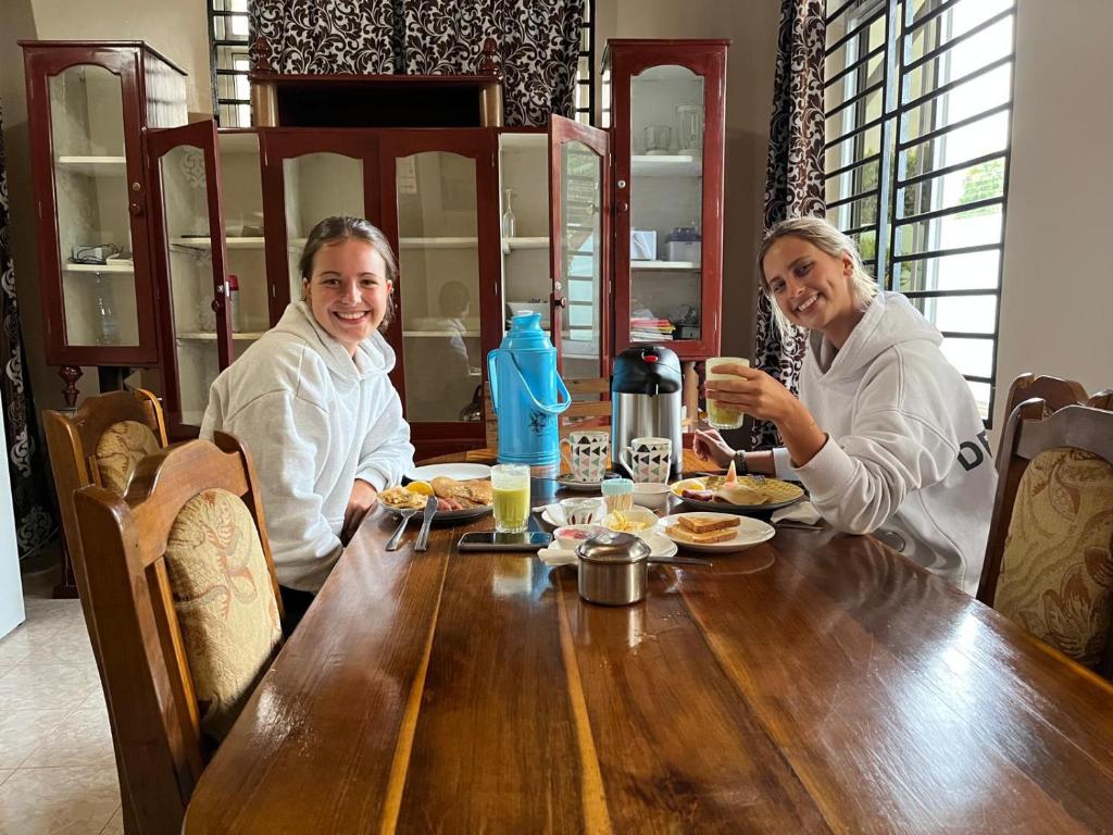 two people sitting at a wooden table with food at The Secret Garden Hotel Moshi in Moshi