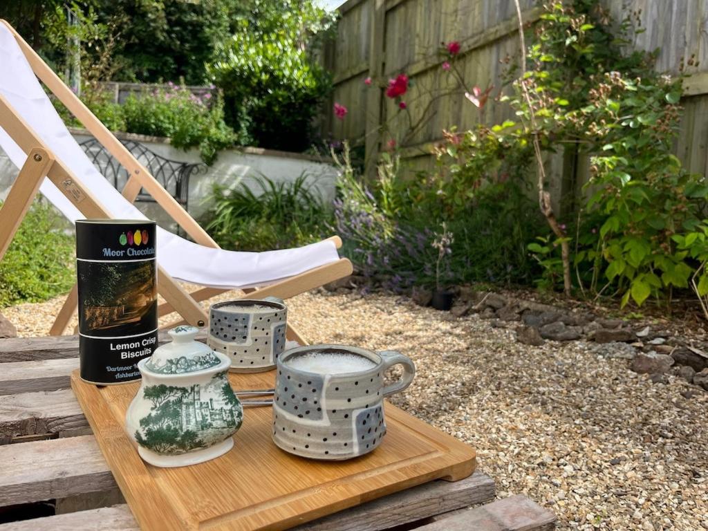 a wooden table with vases and a book on it at Bungalow on Dartmoor's Edge, Parking & Garden in Ashburton