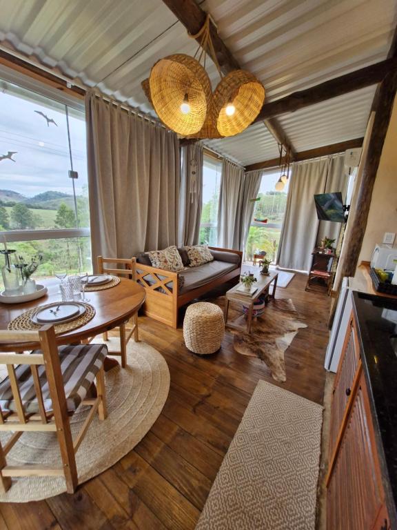un soggiorno con un tavolo e un divano di Chalé Girassol - Vila Monte Cunha a Cunha
