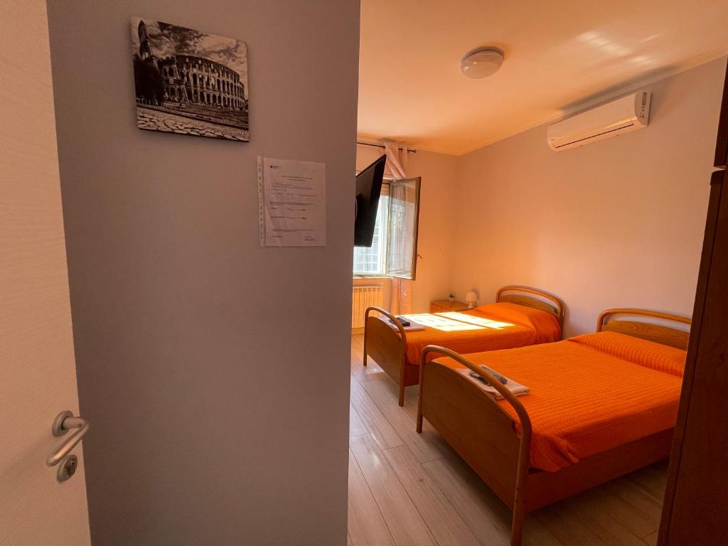 a room with two beds with orange sheets at Afficamere Mattia Mottola 1 in Fiumicino