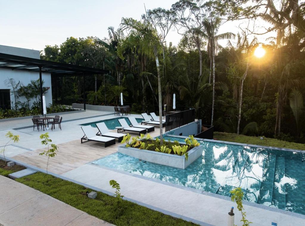 a swimming pool with benches and tables next to a house at Refúgio Amazônico com Piscina e Natureza in Manaus